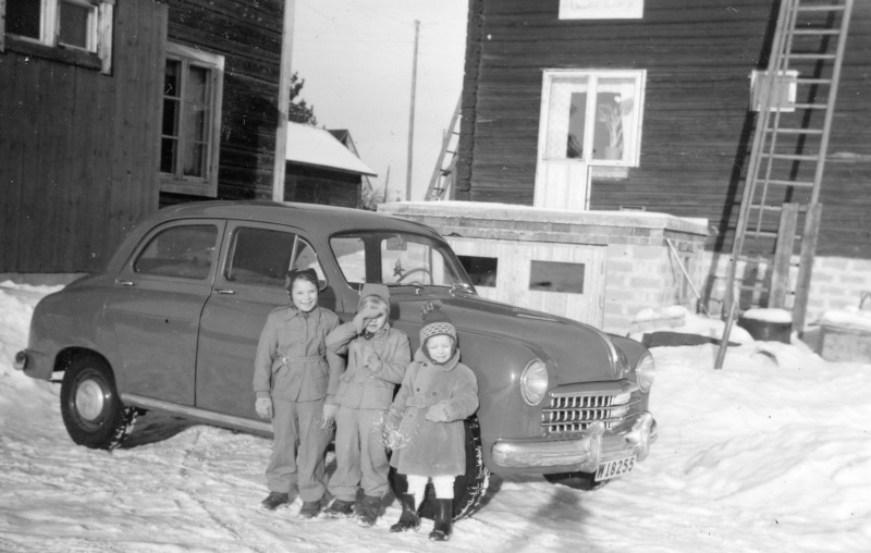 Tre barn framför bilen